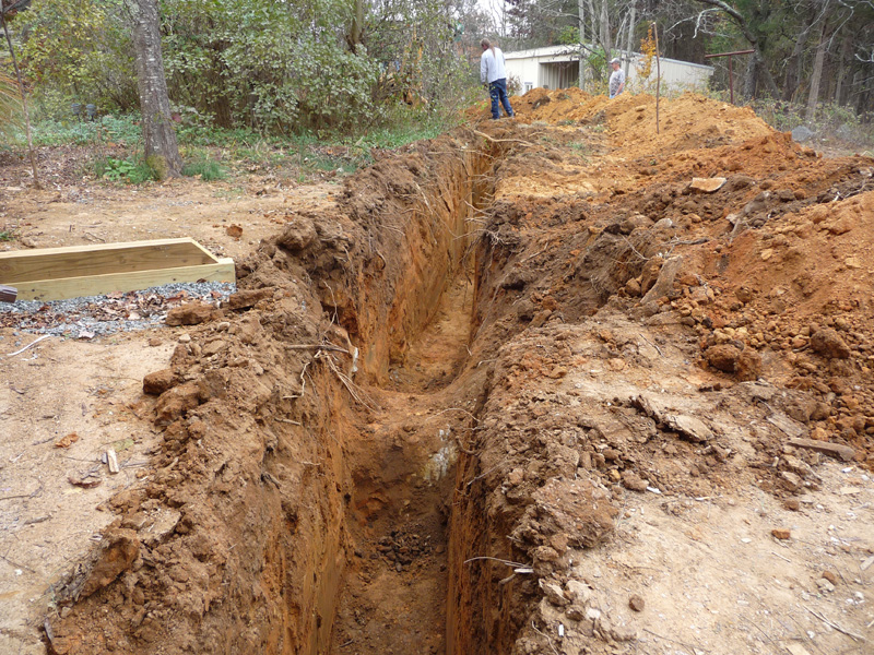 Trench for geothermal piping, with rock