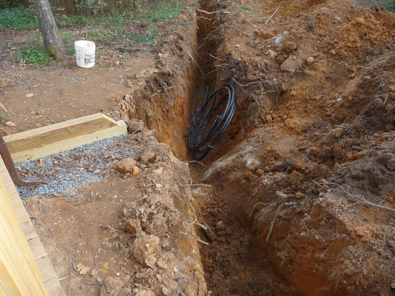 Geothermal pipe next to rock in trench